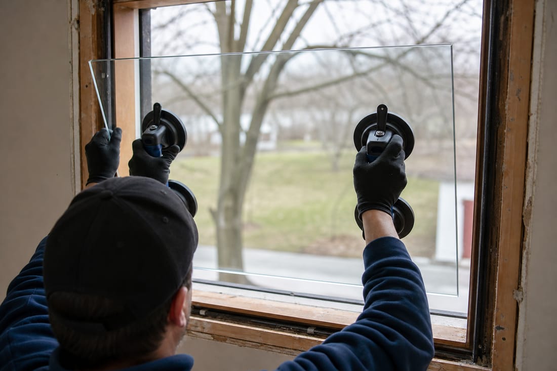 Beispiel: Glaser setzt Glas in einen Fensterrahmen ein